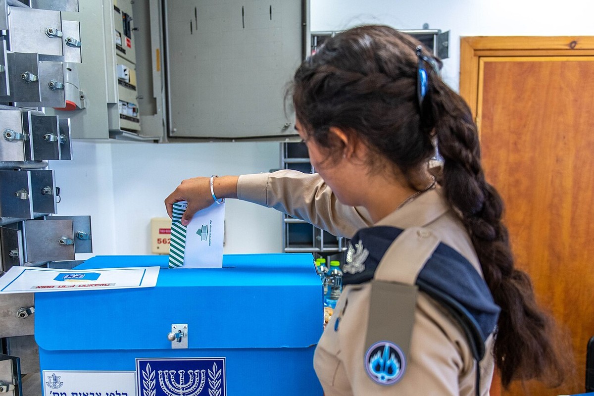 Israeli Air Force soldier placing a ballot envelope into a ballot box