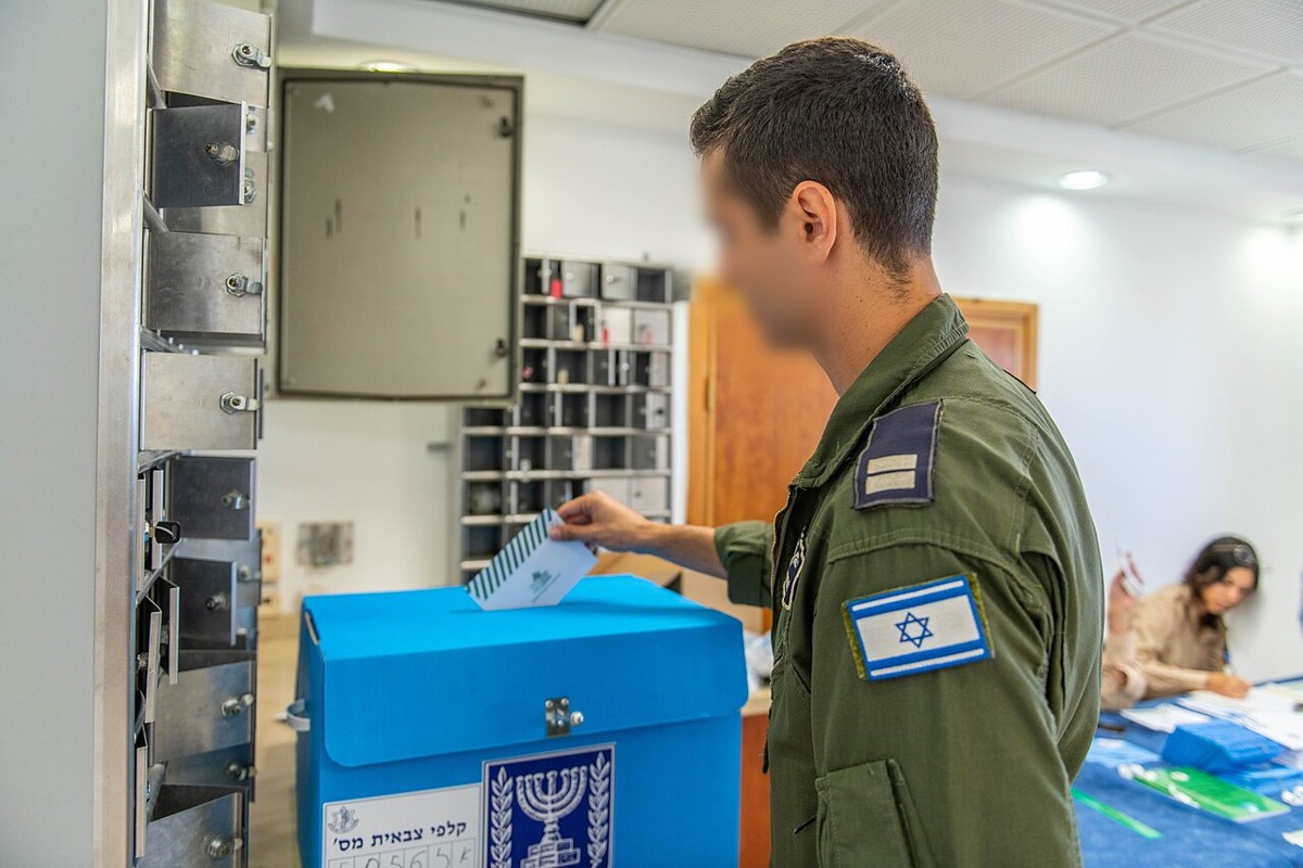 Israeli soldier placing a ballot envelope into a ballot box